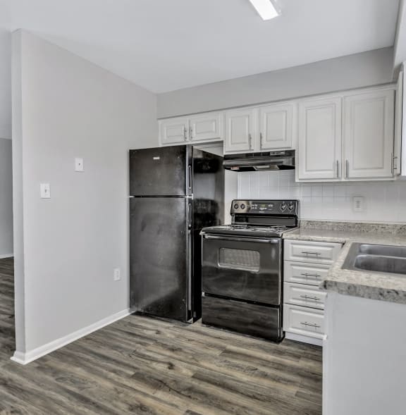 an empty kitchen with white cabinets and a black refrigerator