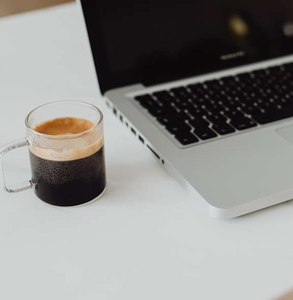 A laptop is open with a mug of coffee in front of it.