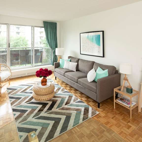 A living room with a grey couch, a round table, and a television.