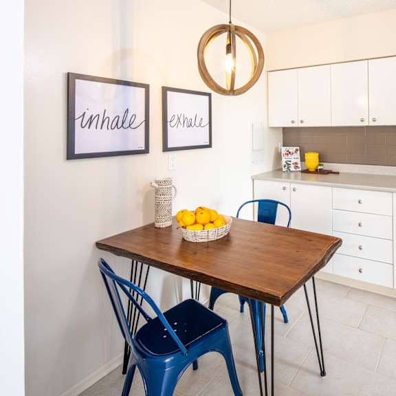 A kitchen with a table and chairs and a fridge.