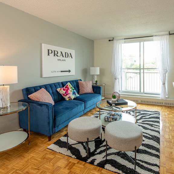A living room with a blue sofa and a Prada sign on the wall.