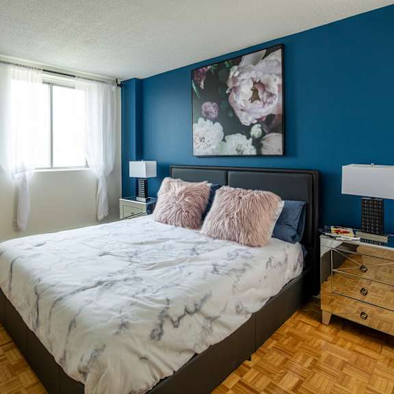 A bedroom with a large bed and a painting on the wall.