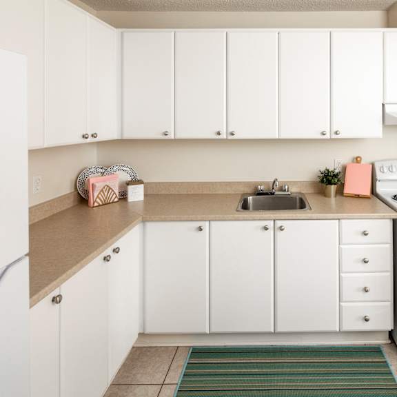 A white kitchen with a stove, sink, and cabinets.