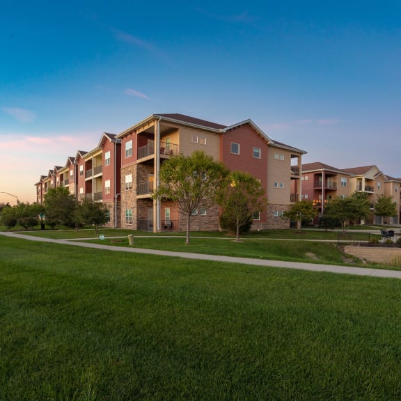 a pathway leading to an apartment building on a grass field