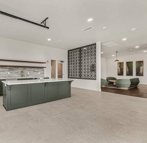 A modern kitchen with dark green cabinets and a stone backsplash.