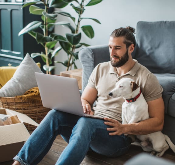 a man sitting on the floor with a dog and a laptop  at The Griffin Royal Oak, Royal Oak, Michigan