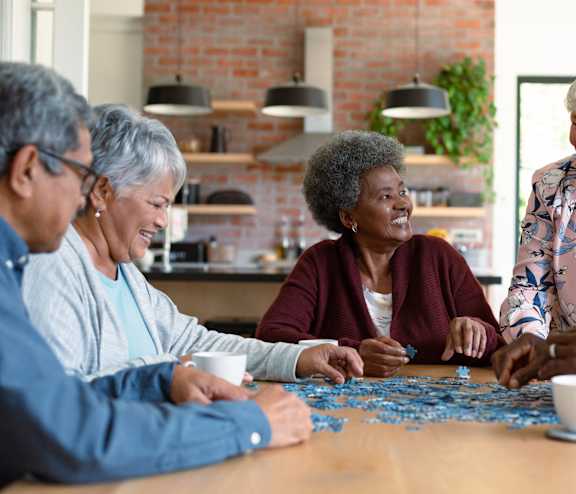 a group of people sitting around a table playing a jigsaw puzzle