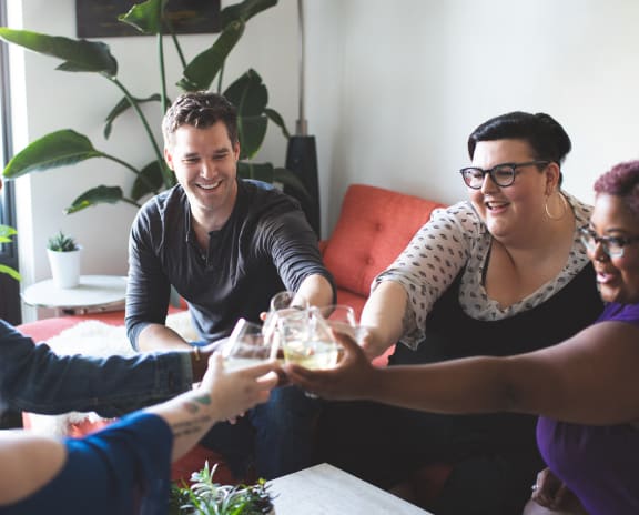 a group of people sitting around a living room holding wine glasses