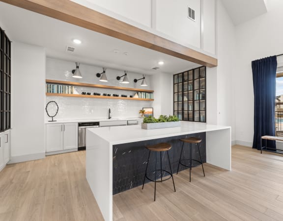 a kitchen with a large white island with three stools