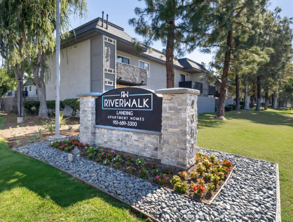 a building with a sign in front of a lawn and trees