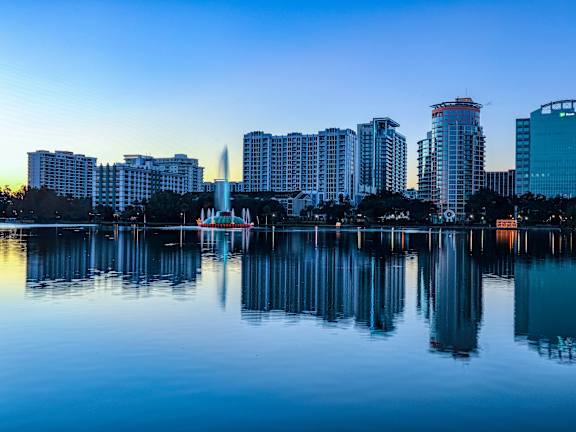 A city skyline is reflected in the water in front of it.