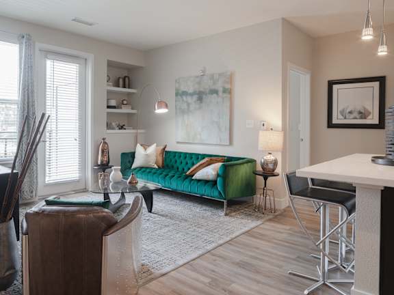 A living room with a green couch and a painting on the wall.