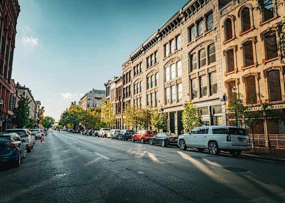 A street with cars parked on the side and buildings on both sides.
