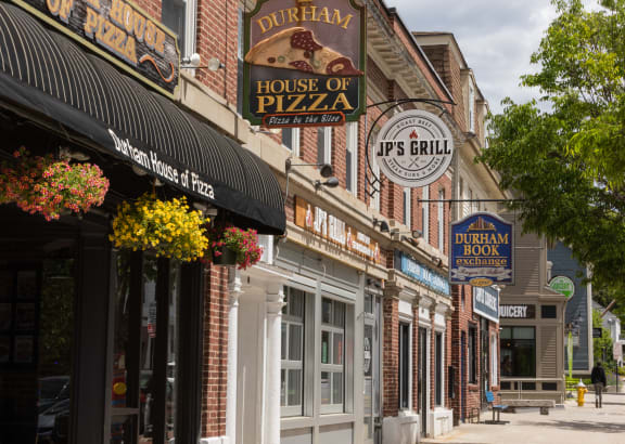 a city street with brick buildings and a sign that reads house of pizza