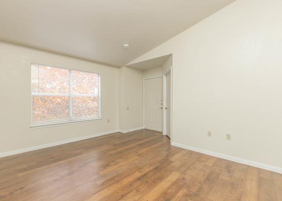 A room with wooden floors and a window with a view of trees outside.