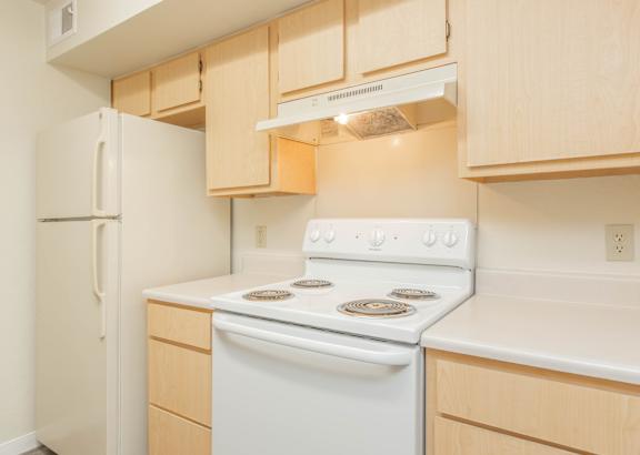 A white stove and refrigerator in a kitchen with wooden cabinets.