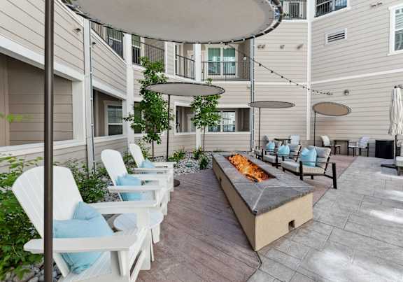 A patio with white chairs and a fire pit.