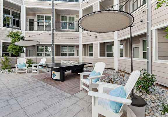 A patio with a table and chairs and a white umbrella.