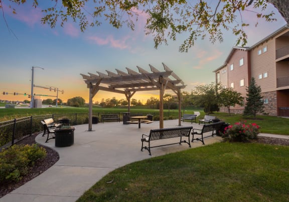 a park with benches and a pavilion at sunset