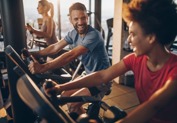 a man and a woman biking on an exercise bike in a gym