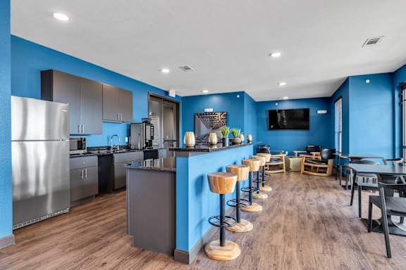 a communal kitchen and dining room with a bar and stools
