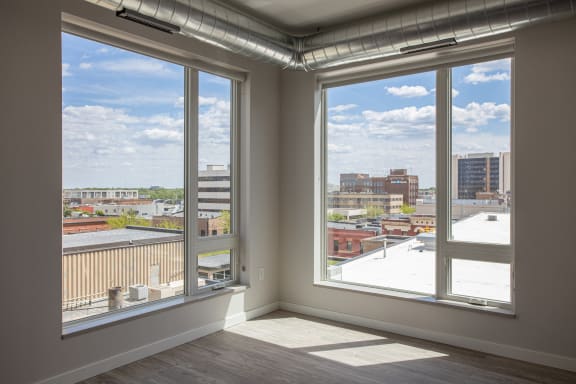 A living room with large windows and a view of a city at Kesler Apartments in Downtown Fargo, Fargo, ND 58102