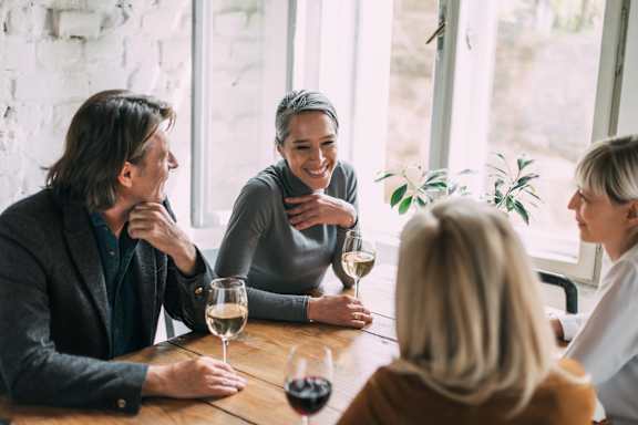 A group of people are sitting around a table with wine glasses in front of them.