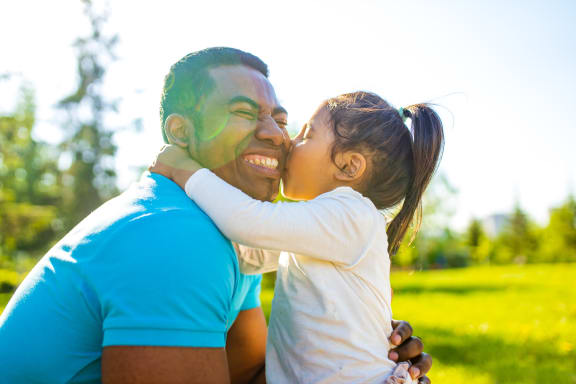a little girl kissing a man on his face