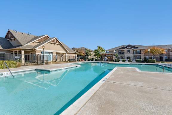 A large outdoor swimming pool surrounded by trees and a building.