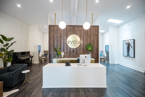 a reception area with a white desk and a logo on the wall