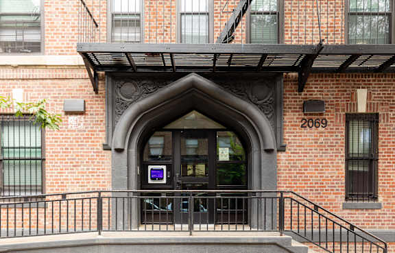 A brick building with a black arched entrance and a staircase leading to it.