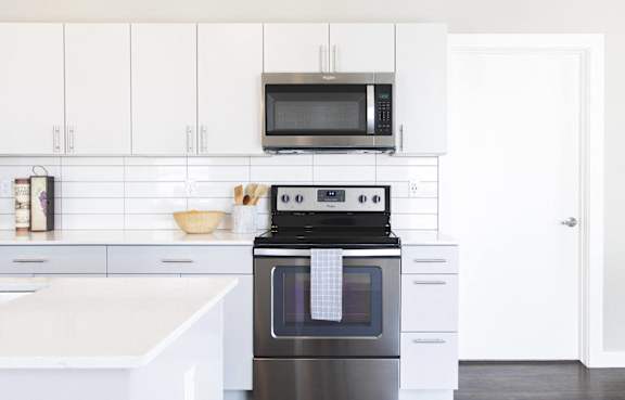 a white kitchen with stainless steel appliances and a microwave