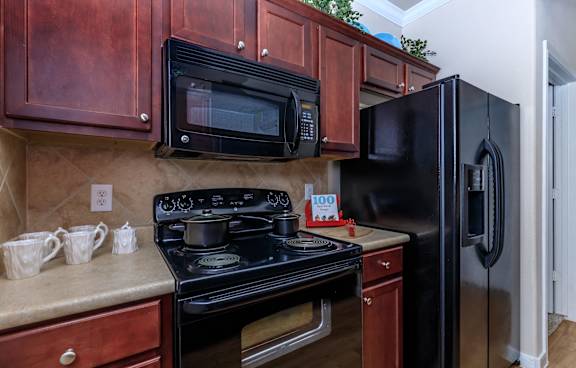 A black refrigerator is in a kitchen with a black stove and black microwave.