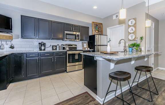 A kitchen with black cabinets and a white island.