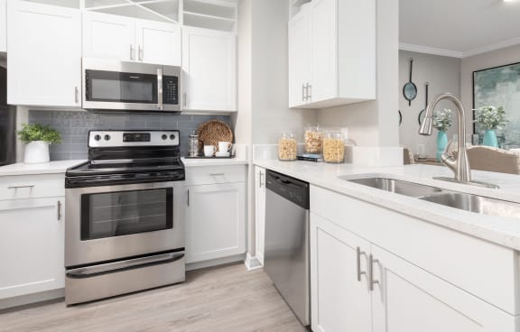 a white kitchen with stainless steel appliances and white cabinets