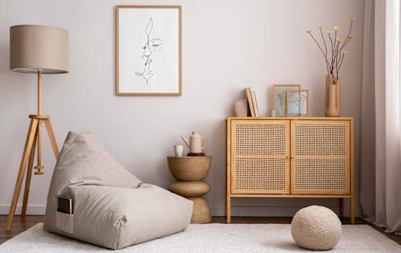 A modern living room with a beige chair, a wooden cabinet, and a white rug.