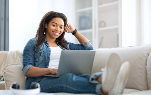 An older woman and a younger girl are sitting on a couch looking at a tablet.