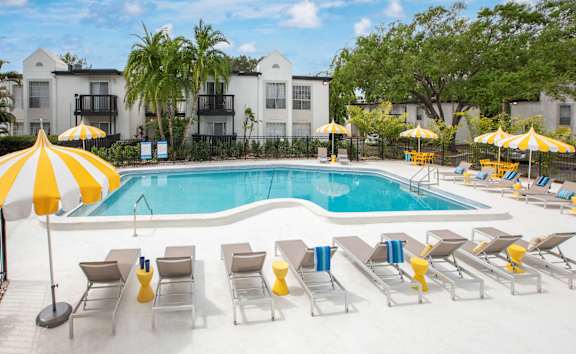 A pool surrounded by yellow umbrellas and lounge chairs.