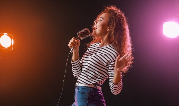 a woman singing into a microphone on a stage