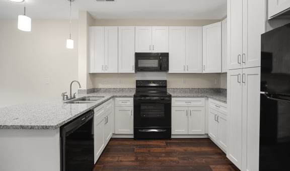 an empty kitchen with white cabinets and black appliances