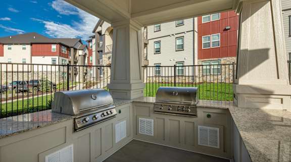 a covered outdoor kitchen with two stainless steel grills