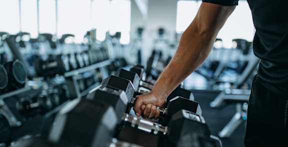 A person is lifting dumbbells in a gym.
