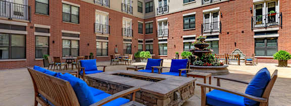 A pool with a green umbrella and chairs.