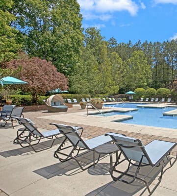 a swimming pool with lounge chairs and umbrellas