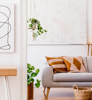 A living room with a grey couch, a wooden table, and a large abstract painting on the wall.