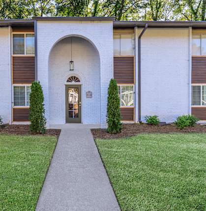 the front of a building with a sidewalk and grass