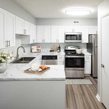 A modern kitchen with white cabinets and stainless steel appliances.
