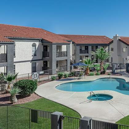 A swimming pool in front of a building with a black fence around it.