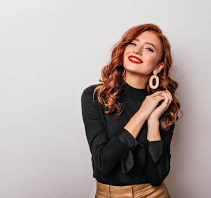 a young woman wearing red lipstick and a black shirt and gold skirt