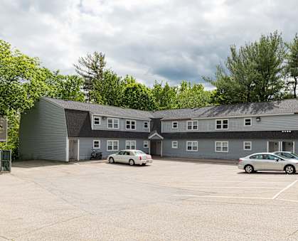 a photo of the front of a building with a parking lot in front of it
